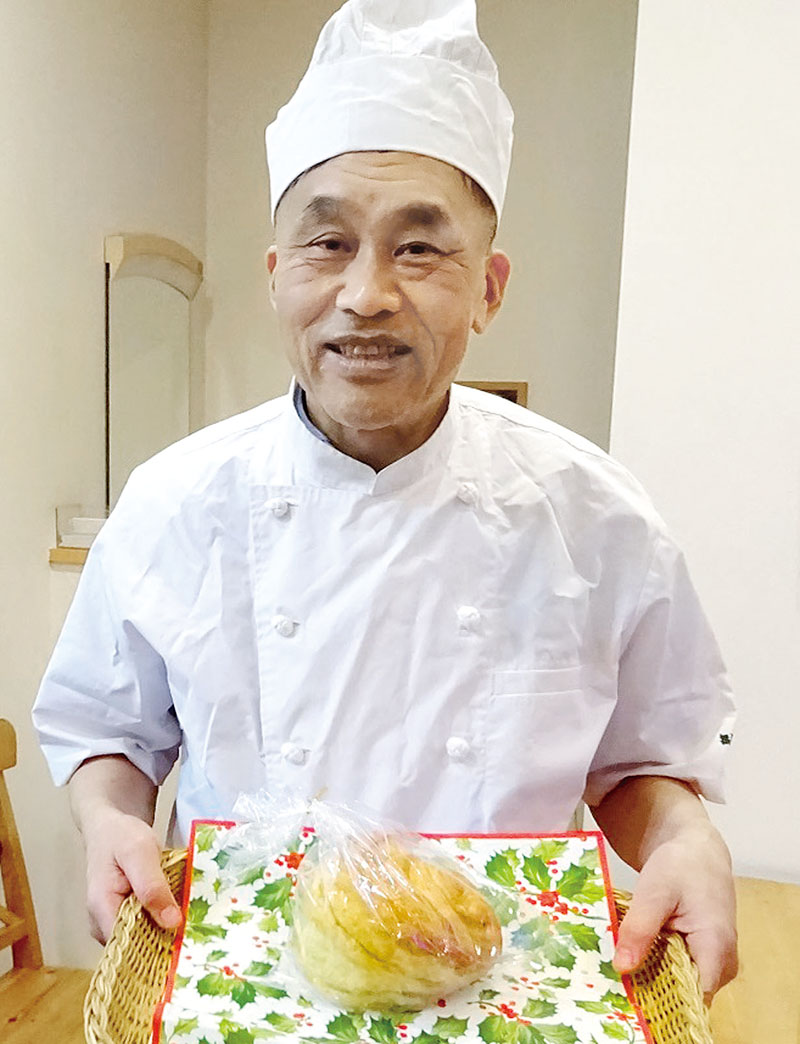 ユニークな形の切り株パンを持つ秋本さん