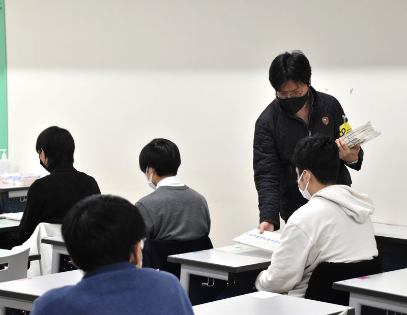 受験者に問題用紙を配布する試験監督者＝14日午前9時過ぎ、さいたま市桜区の埼玉大学