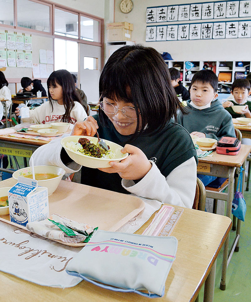 給食でご飯に盛られた鯨肉の甘酢あんかけを食べる女子児童＝富士見市立諏訪小学校