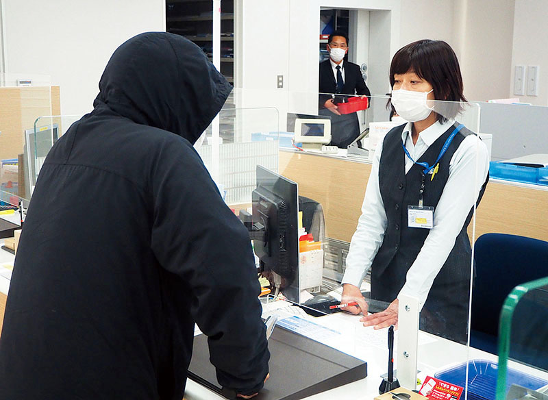 訓練で犯人役に刃物を突き付けられ、動揺した様子を見せる職員＝16日、さいたま市見沼区の埼玉縣信用金庫大和田支店・七里支店