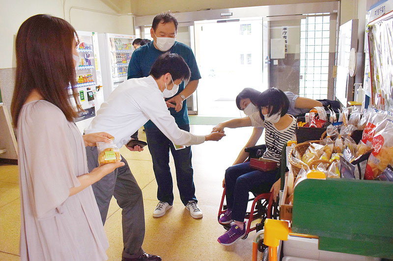 店舗からワゴンで商品を運び県庁職員に販売する障害者団体・施設の利用者ら＝2022年6月13日、埼玉県庁