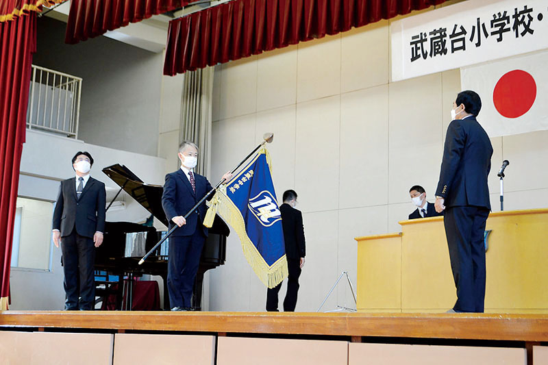 中学校の校旗を持つ秋馬信之校長（左から2人目）＝7日午後、日高市立武蔵台中学校