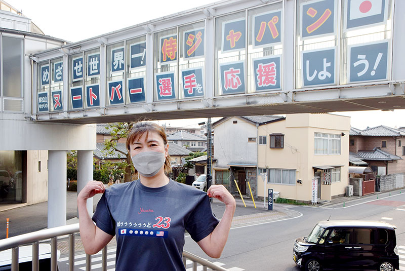 連絡通路の外壁にお目見えした応援メッセージとヌートバー選手の応援Tシャツを着た金子清美さん＝9日、東松山市役所前