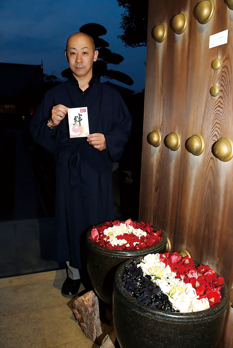 （手前から）シリア、トルコそれぞれの国旗をデザインした花手水と特別に頒布する御朱印を持つ千田明寛さん＝9日、川越市小ケ谷の最明寺