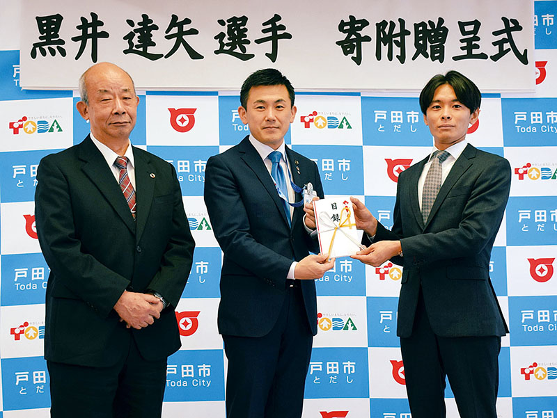 菅原文仁市長（中央）に寄付目録を手渡した黒井達矢選手。左は戸ケ崎勤教育長（右）＝20日、埼玉県戸田市