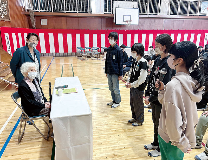 東京大空襲の体験を講演した名倉幸子さん（左）と感想を話す子どもたち。左奥は森裕子校長＝9日午前、さいたま市中央区の与野本町小学校