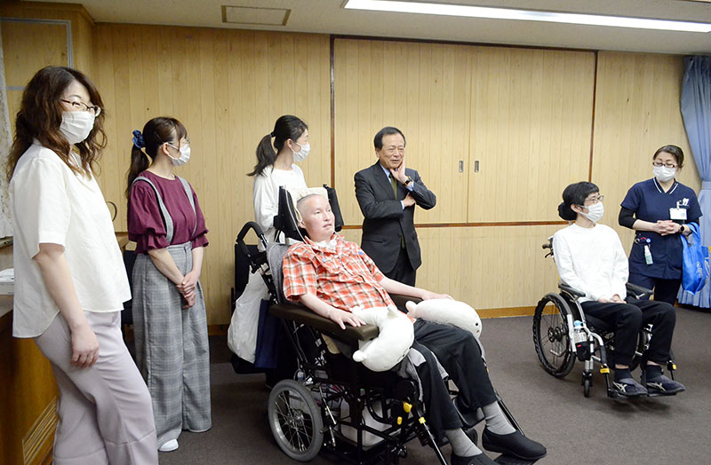 県庁を訪れた中村秀之さん（左から3人目）や松尾建治さん（右から2人目）と家族やヘルパー、医療従事者ら＝21日、県庁