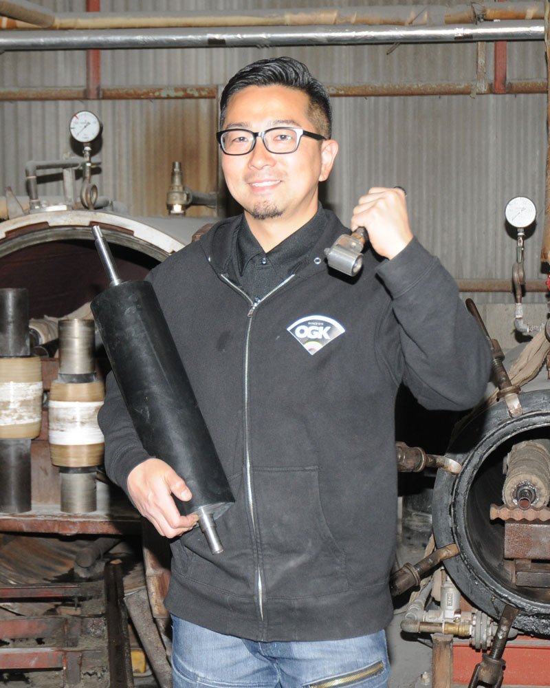 ゴム製造を「クリエイティブな仕事だと思っている」と自負する扇ゴム工業の川田大輔代表。後方はゴムを蒸す加硫窯