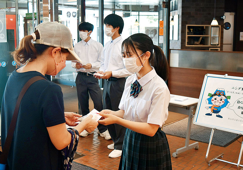 塩あめと熱中症予防リーフレットを配布する生徒たち＝4日、埼玉県熊谷市銀座のニットーモール