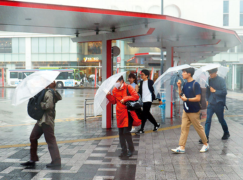 強まる雨風の中、傘をしっかり持って歩く人たち＝8日午後1時48分ごろ、埼玉県さいたま市浦和区のJR浦和駅東口