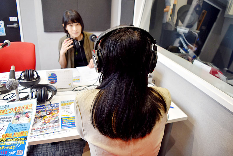 FMクマガヤのスタジオで生放送に出演し、情報提供を呼びかけた母親（手前）＝21日午後3時45分ごろ、熊谷市筑波のアズ熊谷6階