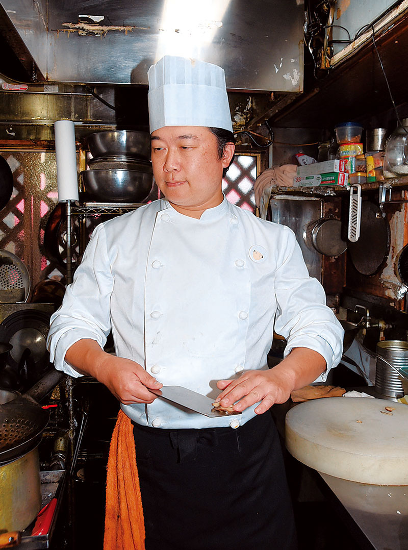 白衣に白い帽子姿で調理する料理長の田村義明さん＝鶴ケ島市藤金の「中国料理　蔵王飯店」