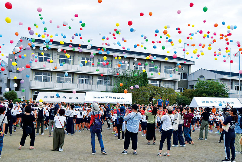 風船を飛ばす「バルーンリリース」を行う参加者たち＝熊谷市立別府小学校