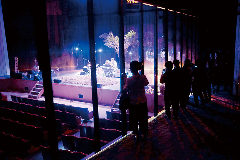 芸術祭のオープニングを飾るテリー・ライリーさんによるリハーサルの様子を透明の板越しに眺める人たち＝6日午後、埼玉県さいたま市大宮区の旧市民会館おおみや
