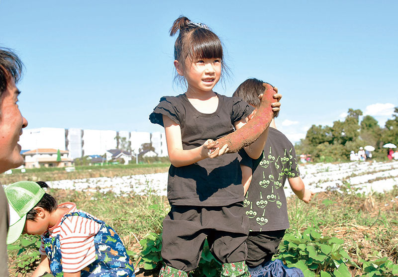 収穫した芋を見せる参加者＝加須市のむさしの村