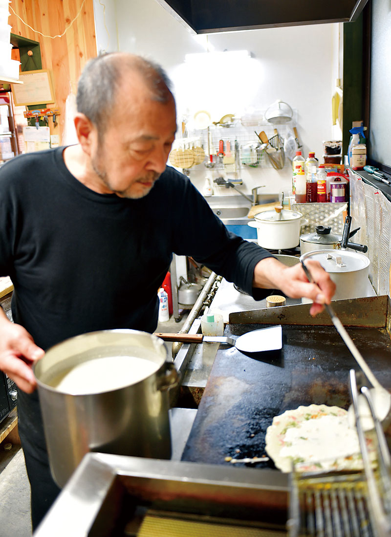 フライを焼く飯嶋隆夫さん。生地に行田在来の青大豆の粉末を入れ、もちもち感を出している＝埼玉県行田市本丸のたかお家