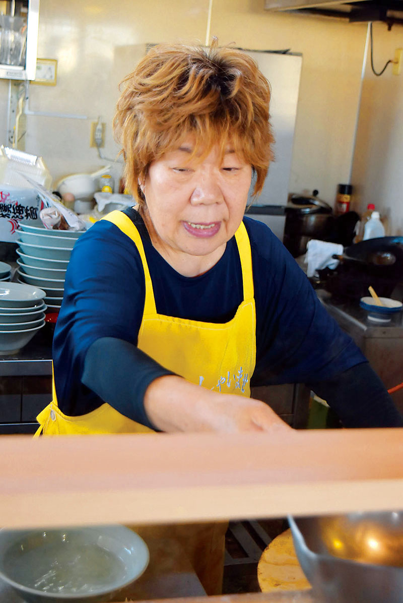 厨房（ちゅうぼう）に立つ店主の渡辺久江さん＝行田市小見の「丸信ラーメン」