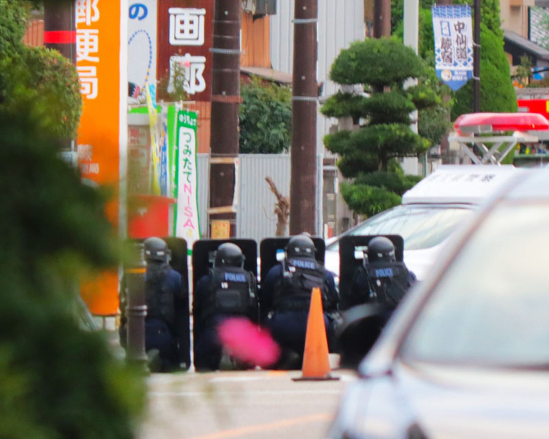 男が立てこもった蕨郵便局の手前で盾を持ち警戒する警察官ら＝10月31日午後4時10分ごろ、埼玉県蕨市中央5丁目