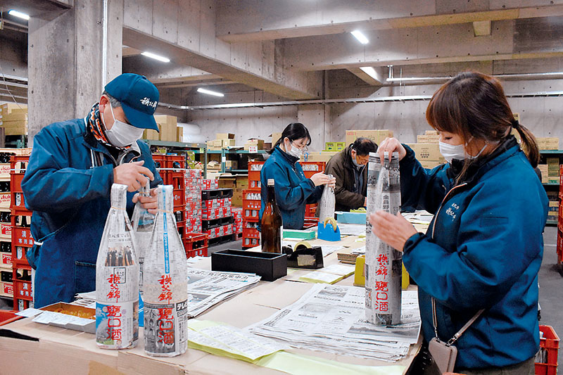 埼玉新聞で甕口酒を包む従業員＝4日午前、秩父市別所の矢尾本店