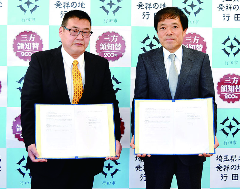 協定書を持つ横田英利副市長（右）と三上昇社長
