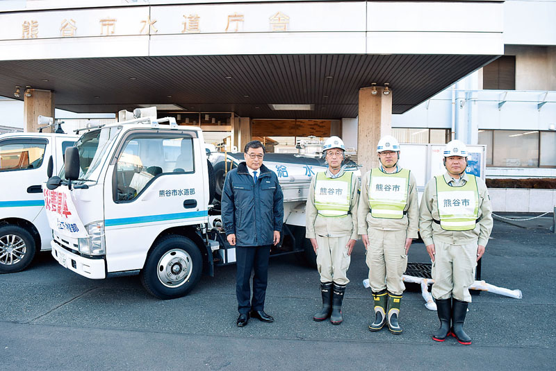 派遣する職員3人を激励した小林哲也市長（左）＝9日午後、埼玉県熊谷市原島の市水道庁舎