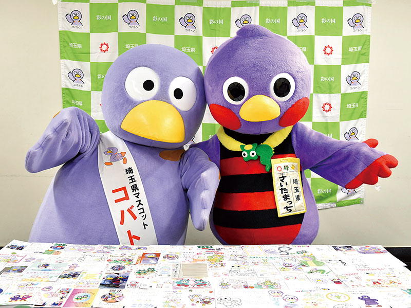 届いた年賀状を披露するコバトン（左）とさいたまっち＝12日午後、埼玉県庁