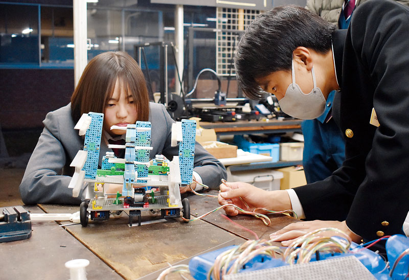 真剣なまなざしでロボットの調整を行う矢野絢音さん（左）と谷将吾さん＝19日午後、さいたま市南区の埼玉大学教育学部付属中学校