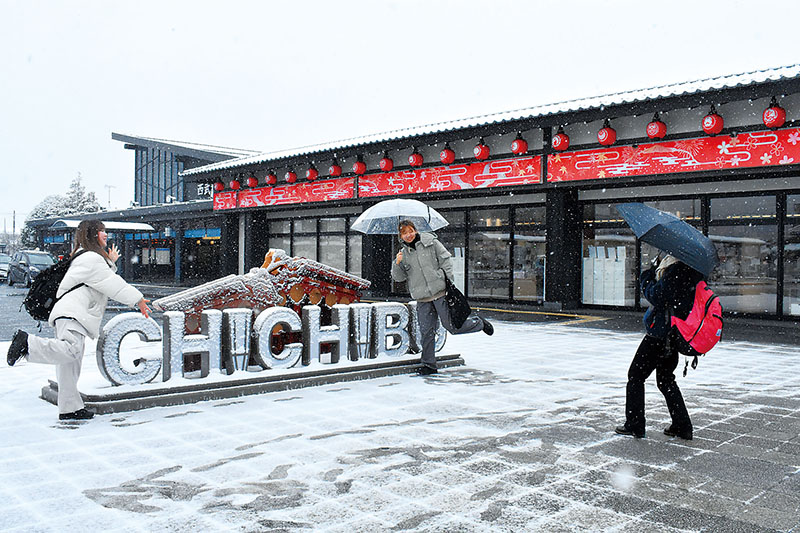 雪が積もり始めた西武秩父駅前で雪景色と記念写真を撮る人たち＝5日午後1時半ごろ、秩父市野坂町