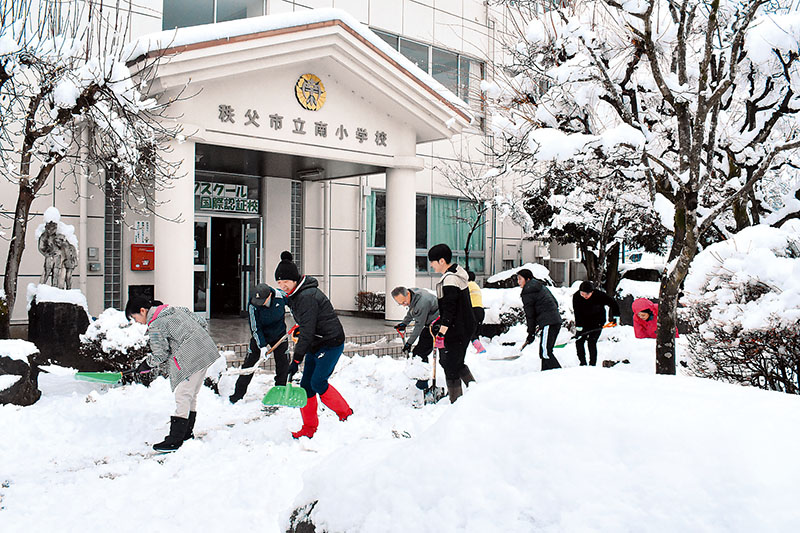 校内の雪かき作業に励む学校職員＝6日午前9時半ごろ、埼玉県秩父市野坂町の市立南小学校