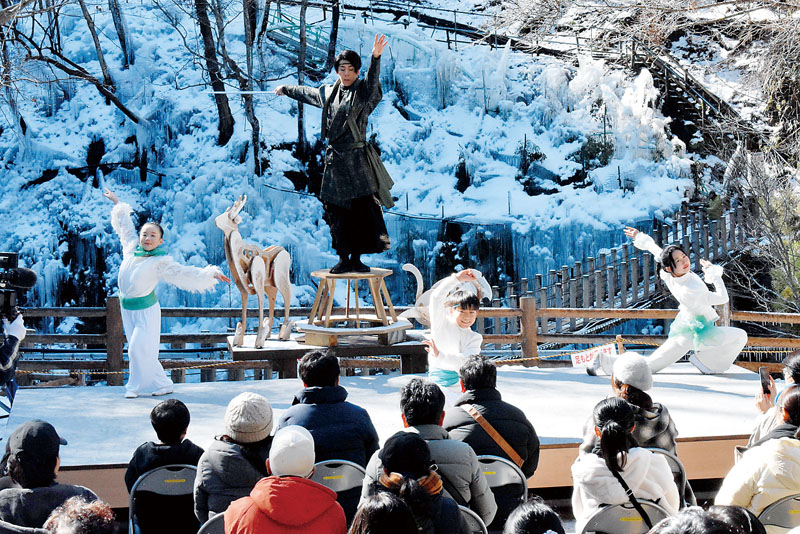 雪と氷柱が輝く舞台でダンスを披露する村岡友憲さんと小学生メンバー＝12日午前、埼玉県小鹿野町の尾ノ内渓谷