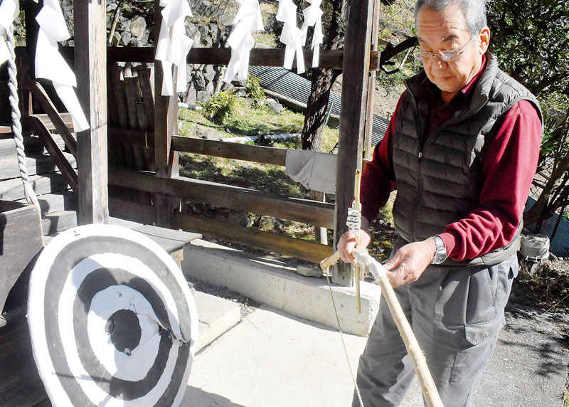 過去に「出原の天気占い」で使用した弓と的を整理する黒沢富夫さん＝17日、小鹿野町両神薄の諏訪神社