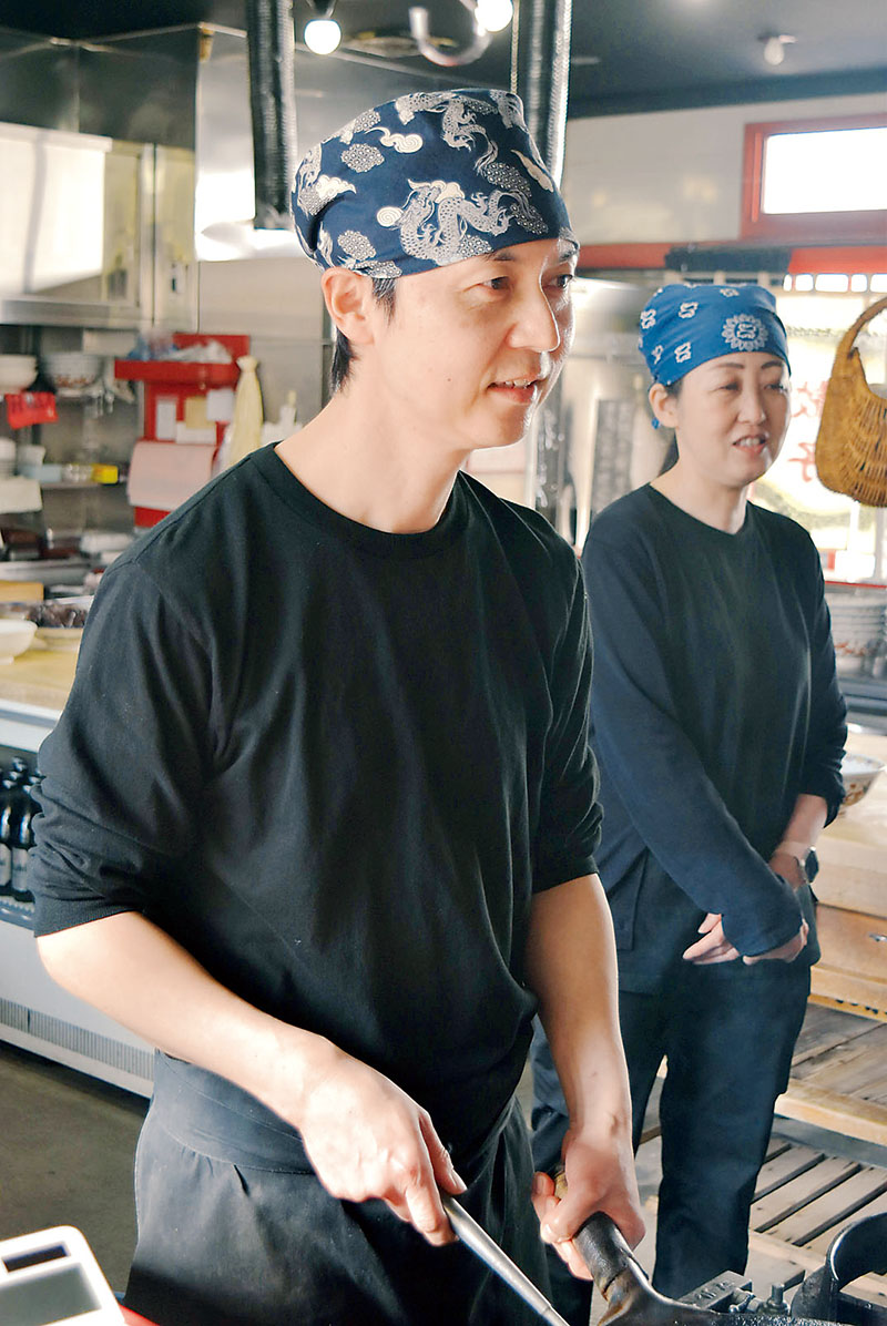 厨房（ちゅうぼう）で鍋を持つ関根臣吾さん（左）と妻の智美さん＝埼玉県熊谷市弥生の「永楽本店」