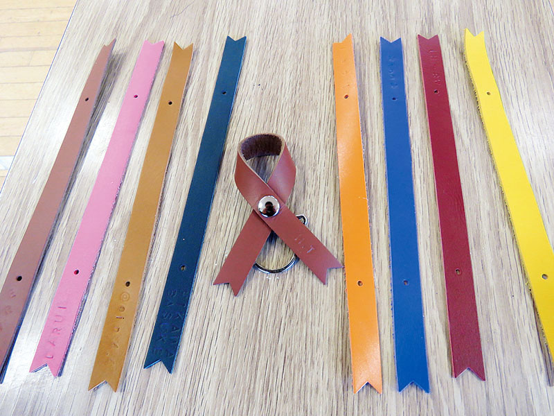 完成品のリボン（中央）と使用した8色の皮革