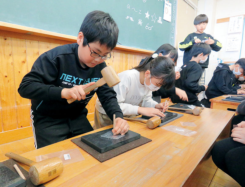 ハンマーでたたいて刻印する児童＝13日午前、草加市立谷塚小学校