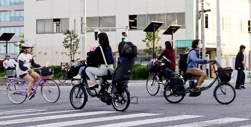 自転車で行き交う人々。ヘルメット着用者は少ない＝4月25日午後、埼玉県さいたま市大宮区