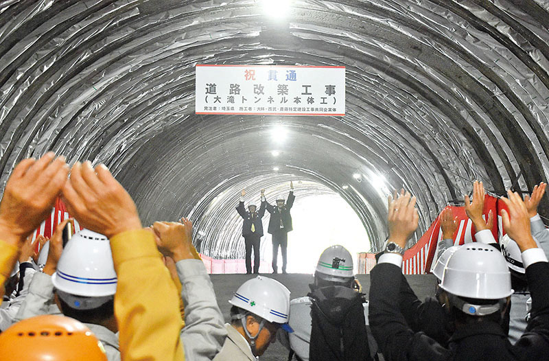 無事故の貫通成功を祝し、万歳三唱する関係者＝15日午前10時半ごろ、秩父市の大滝トンネル