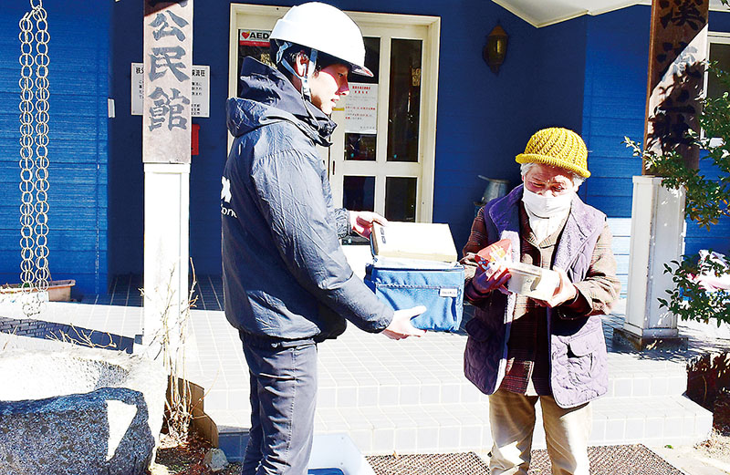 ドローンで運ばれた商品を、浦山地区の市老人福祉センター渓流荘で受け取る浅見ケイ子さん（右）