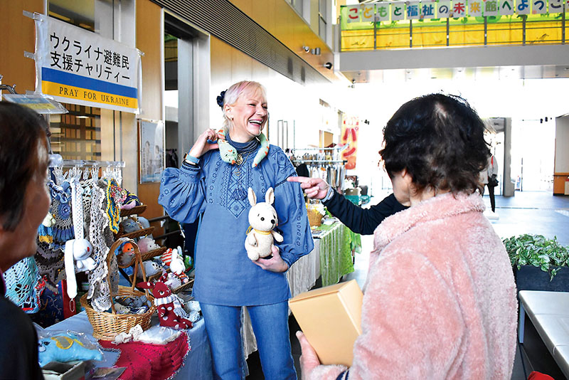 バザーで手作り商品について説明するクリスティーナさん（中央）