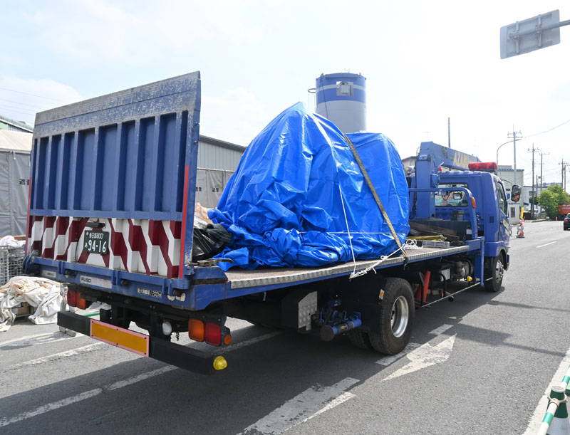 ブルーシートに囲われたトラックの運転席部分＝16日午前、八潮市中央