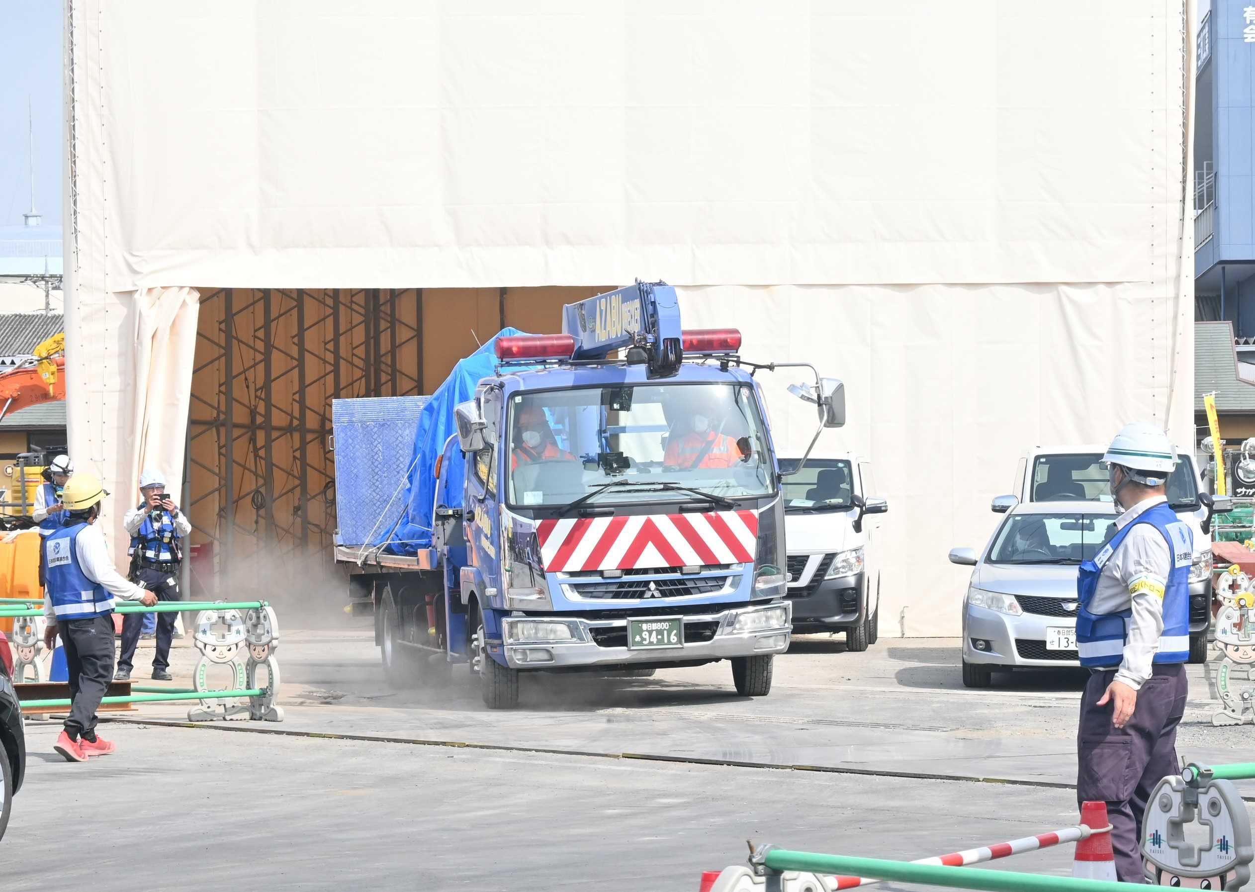 テント内からトラックの運転席部分を搬出する車両＝16日午前、八潮市中央