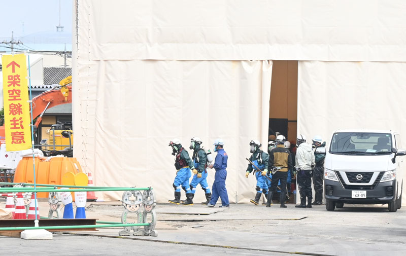 テント内から出てくる作業員ら＝16日午前、八潮市中央