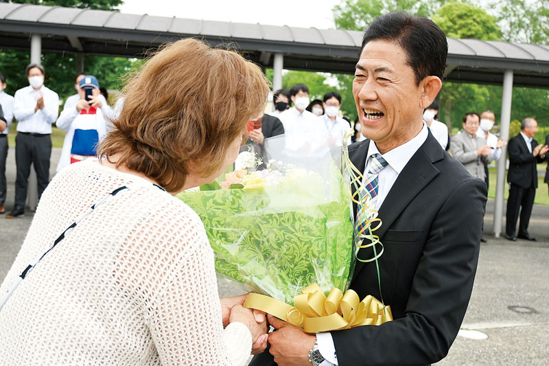町役場に初登庁し、支持者の女性から花束を贈られる藤間隆町長＝19日午前10時半ごろ、川島町役場