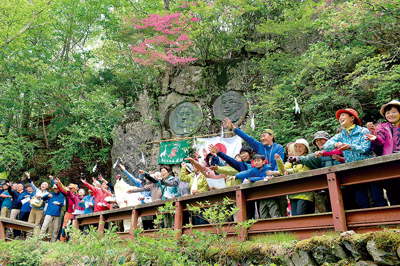 谷に向かって切麻をまく登山者ら＝1日正午ごろ、秩父市霧藻ケ峰の秩父宮両殿下レリーフ前