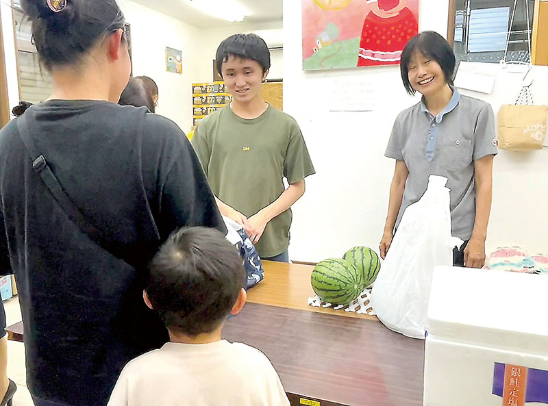 フードパントリーを利用し、食料品を受け取る親子＝7日、越谷市