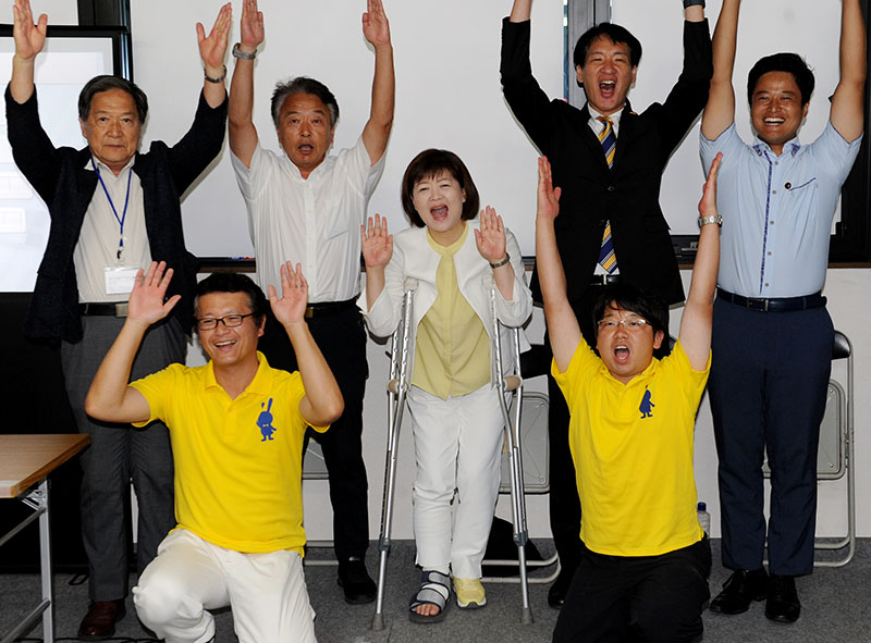 当選確実の速報を受け、万歳して喜ぶ江原久美子氏（中央）＝20日午後8時5分ごろ、さいたま市中央区の選挙事務所