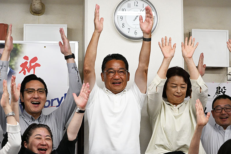 接戦で再選を決め、支援者らと万歳する熊谷裕人氏（中央）＝21日午前1時5分ごろ、さいたま市大宮区の選挙事務所