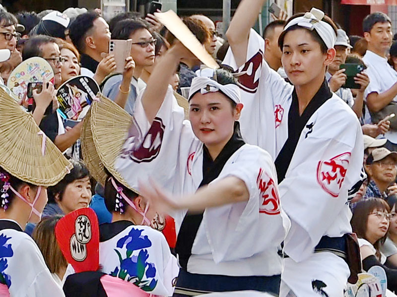 大勢の見物客の前で威勢よく踊る演者ら