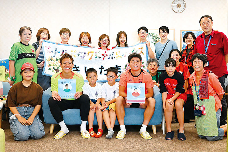 「さいたまハウス」の利用者、スタッフと共に笑顔で記念撮影をする西川周作選手（前列左から2人目）と照内利和選手（同右から3人目）＝25日、さいたま市中央区の県立小児医療センター