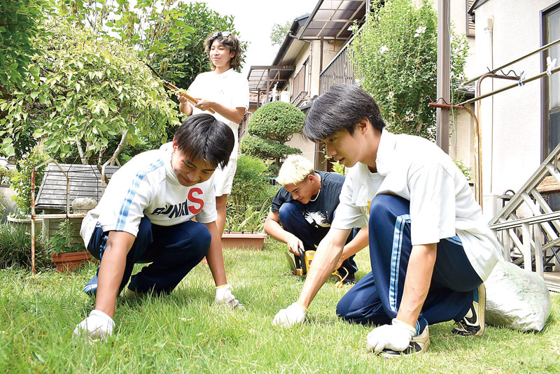 近隣住民の家の庭で除草作業を行う生徒ら＝8月28日午前、狭山市柏原