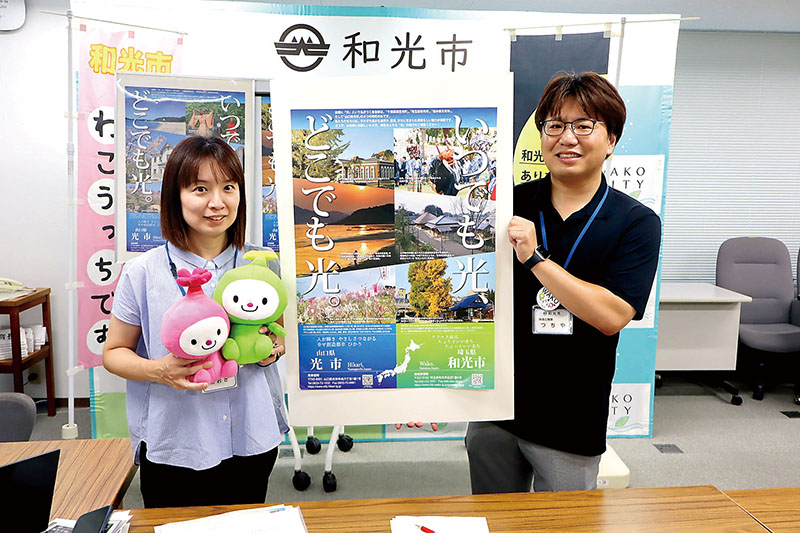 山口県光市と和光市の名所の写真などを掲載した観光PRポスターを持つ和光市職員＝和光市役所